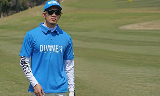 青と白のゴルフウェアを着てサングラスをかけた筋肉質の男性